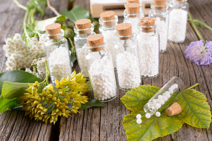 Homeopathic lactose sugar globules in glass bottles with plants